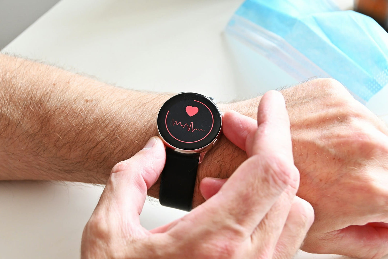 Smartwatch with heart rate monitor on a wrist, held by hands.