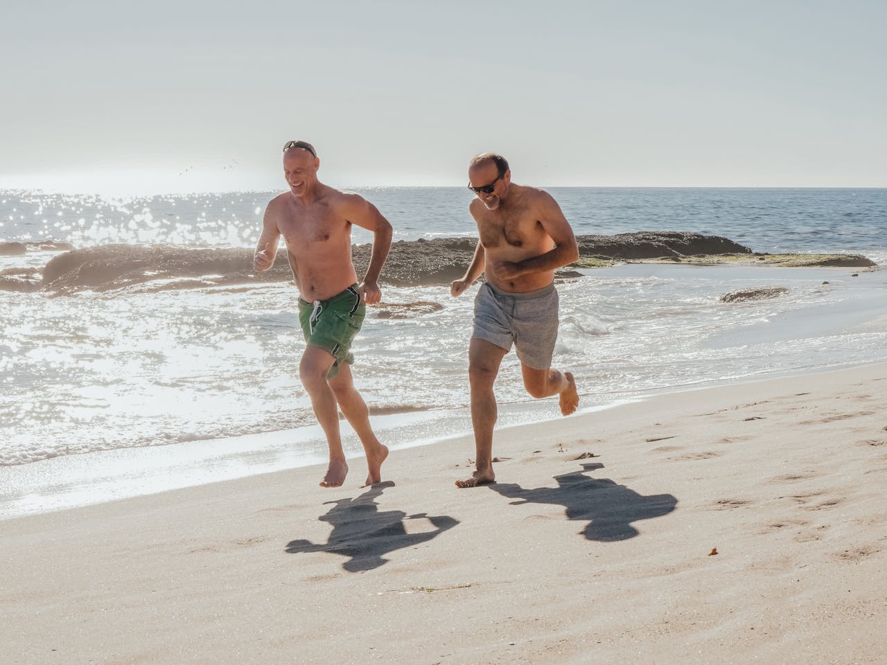 Two men running on a beach with ocean in the background